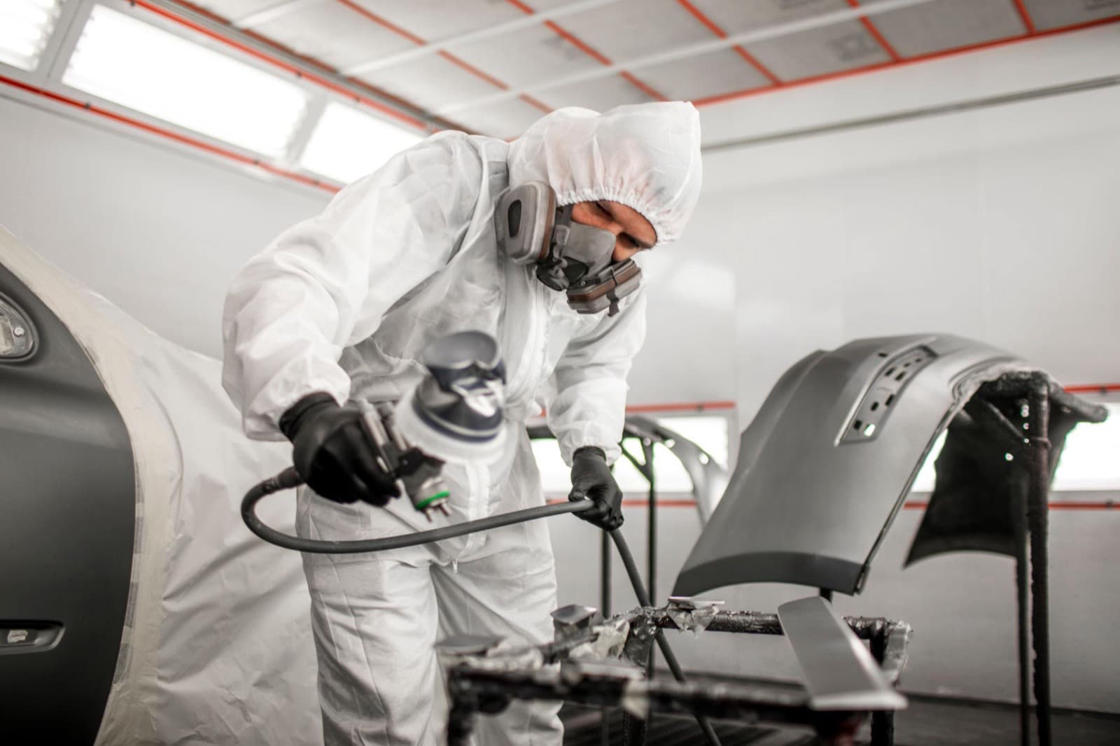 Color Crafters paint booth with technician spraying a masked panel
